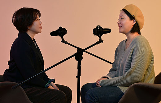 woman-in-a-yellow-hat-interviewed-against-a-gradation-background