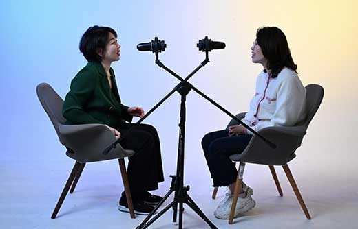 a-long-haired-woman-and-an-interviewer-on-a-blue-yellow-background