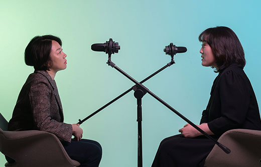 a-short-haired-woman-and-an-interviewer-on-a-green-blue-background