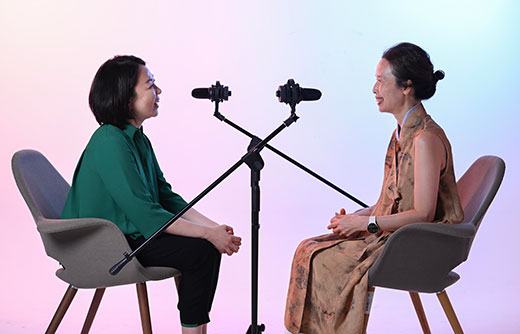 A-photo-of-two-women-interviewing-each-other-with-microphones-and-dramatic-lighting.